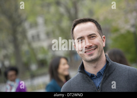 Un groupe de personnes dans un parc de la ville un homme dans un chandail gris smiling Banque D'Images