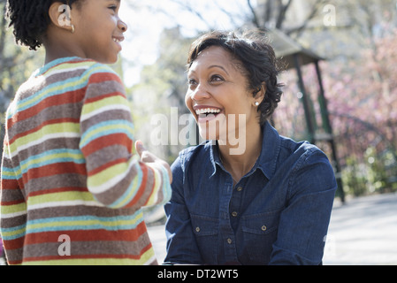 Soleil et cherry blossom une mère à genoux souriant à son fils Banque D'Images