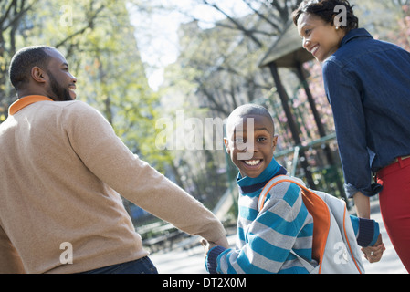 Soleil et fleur de cerisier Un garçon regardant par-dessus son épaule entre ses parents Banque D'Images