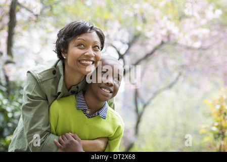 Soleil et cherry blossom une mère et son fils hugging and laughing Banque D'Images