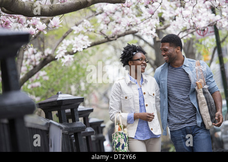 Un couple en train de marcher dans le parc à côté de l'autre carrying shopping bags Banque D'Images