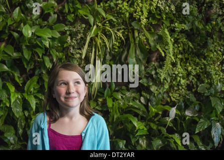 Ville au printemps un mode de vie urbain une jeune fille debout devant un mur recouvert de fougères et plantes grimpantes Banque D'Images