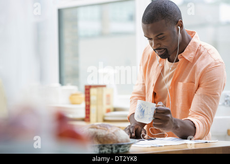 Un homme dans une chemise orange lors du petit-déjeuner barres ayant une tasse de thé Banque D'Images