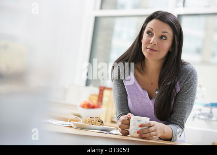 Un bureau ou un appartement à New York de l'intérieur une jeune femme avec de longs cheveux noirs ayant une tasse de café Banque D'Images