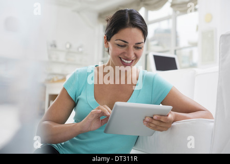 Une jeune femme assise confortablement dans un quartier aéré environnement de bureau à l'aide d'une tablette numérique Banque D'Images