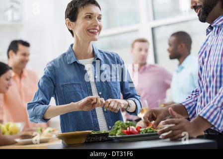 Un bureau en espace ouvert d'un déjeuner de travail, un buffet de salades de tous âges et ethnies ensemble réunion Banque D'Images