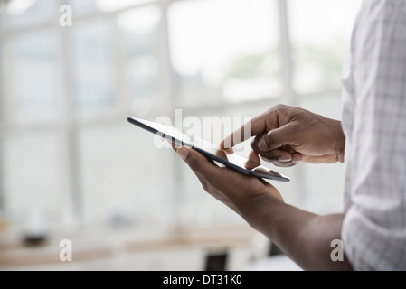 Professionnels à l'office un endroit clair et spacieux de travail un homme en chemise blanche à l'aide d'une tablette numérique Banque D'Images