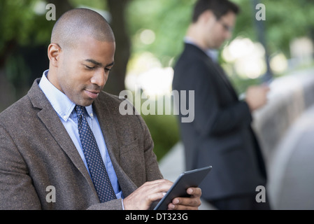 L'homme à l'aide d'une tablette numérique et un contrôle d'un smart phone Banque D'Images