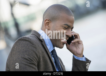 Un homme assis sur un banc pour faire un appel sur son téléphone intelligent Banque D'Images