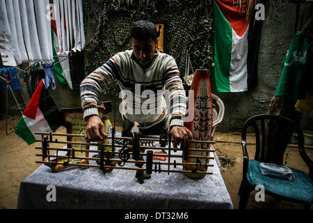 Gaza, Territoires palestiniens. Feb 6, 2014. Peuple palestinien Mohammed al-Zomar, qui peint sur les restes de munitions israéliennes, affiche un morceau de son oeuvre dans son atelier, dans le camp de réfugiés de Bureij au centre de la bande de Gaza le 6 février 2014. Al-Zomar dessine et peint sur les restes de munitions israéliennes qu'il a recueillies au cours de 2008-2009 l'offensive de trois semaines à Gaza et pendant les huit jours de conflit en 2012. Les mots arabes sur le missile (R) lire, ''Lorsqu'une fleur s'estompe, un millier de se soulever. © Abed Rahim Khatib/NurPhoto ZUMAPRESS.com/Alamy/Live News Banque D'Images