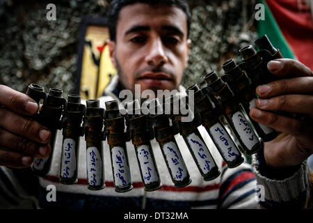 Gaza, Territoires palestiniens. Feb 6, 2014. Peuple palestinien Mohammed al-Zomar, qui peint sur les restes de munitions israéliennes, affiche un morceau de son oeuvre dans son atelier, dans le camp de réfugiés de Bureij au centre de la bande de Gaza le 6 février 2014. Al-Zomar dessine et peint sur les restes de munitions israéliennes qu'il a recueillies au cours de 2008-2009 l'offensive de trois semaines à Gaza et pendant les huit jours de conflit en 2012. Les mots arabes sur le missile (R) lire, ''Lorsqu'une fleur s'estompe, un millier de se soulever. © Abed Rahim Khatib/NurPhoto ZUMAPRESS.com/Alamy/Live News Banque D'Images