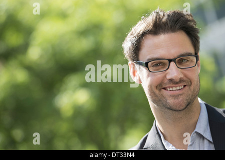 Un homme aux cheveux noirs courts et verres Smiling at the camera Banque D'Images