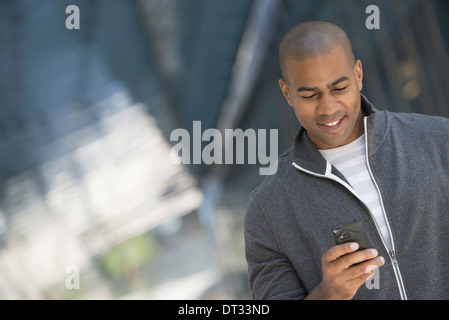 Un homme dans un sweat zippé gris en utilisant son téléphone intelligent Banque D'Images