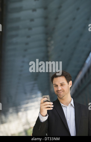 Un homme dans une veste noire et un collier ouvert chemise en utilisant un téléphone intelligent Banque D'Images