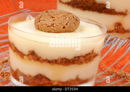 Close-up de la crème vanille et amaretti dessert servi dans des tasses en verre sur un fond orange. Focus sélectif. Banque D'Images