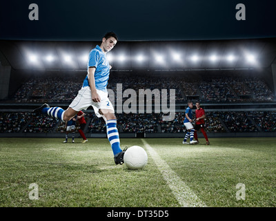 Soccer player kicking ball on field Banque D'Images