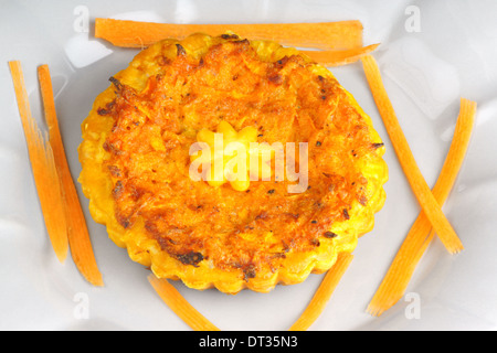 Close-up of a mini quiche végétarienne avec carottes servi sur une assiette de porcelaine gris Banque D'Images