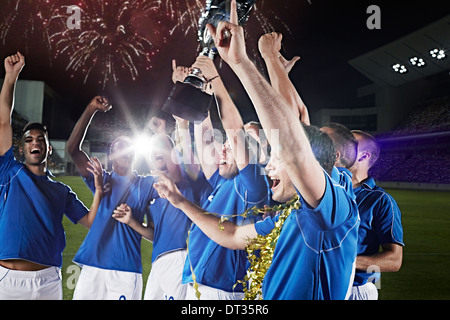 L'équipe de soccer avec acclamations trophy sur terrain Banque D'Images