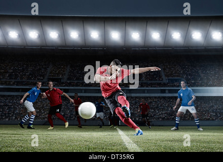 Soccer player kicking ball on field Banque D'Images