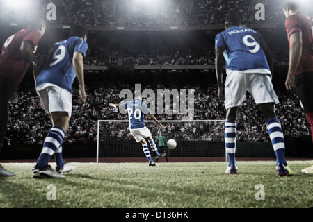 Soccer player kicking ball au but Banque D'Images