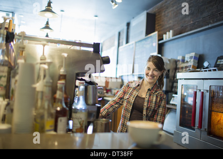 Une personne, d'un barista, derrière le comptoir dans un café. Une machine à café cappuccino sur le comptoir. Banque D'Images