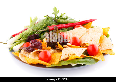 Nachos, tomates cerises, salade, herbes dans la plaque sur fond blanc. Banque D'Images