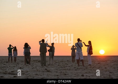 Les touristes à regarder et photographier le lever du soleil à chott El Jerid, grand lac salé dans le sud de la Tunisie. Banque D'Images