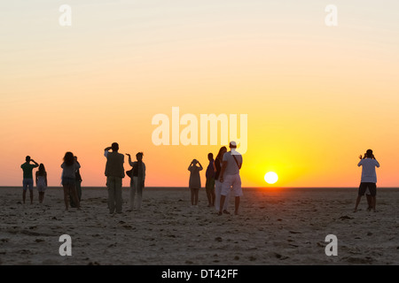Les touristes à regarder et photographier le lever du soleil à chott El Jerid, grand lac salé dans le sud de la Tunisie. Banque D'Images