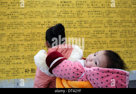 Shanghai, Chine, la Province de Zhejiang. Feb 8, 2014. Une femme à la recherche de renseignements sur l'emploi dans un marché du travail de Zhuji City, Zhejiang Province de Chine orientale, le 8 février 2014. Que la Nouvelle Année lunaire chinoise à la fin des vacances, beaucoup de gens ont commencé à chercher d'emploi récemment. © Guo Bin/Xinhua/Alamy Live News Banque D'Images