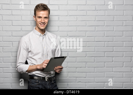 Smiling portrait masculin tablette numérique, appareil photo à la brique studio Banque D'Images