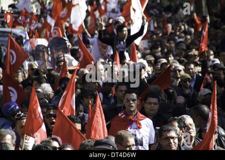 Tunis, Tunisie. Feb 8, 2014. Les manifestants avec le chemin d'un drapeau et d'Tunisie drapeau. À l'occasion de la commémoration du premier anniversaire de l'assassinat de Chokri Belaid, des milliers de personnes se sont réunies à sa tombe au cimetière Al Jalez à Tunis Tunisie le 8 février 2014. Credit : Mohamed Krit/NurPhoto ZUMAPRESS.com/Alamy/Live News Banque D'Images