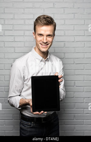 Smiling portrait masculin tablette numérique, appareil photo à la brique studio Banque D'Images