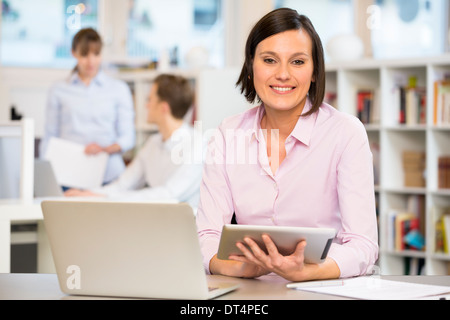 Portrait of smiling female worker, collègues en arrière-plan Banque D'Images