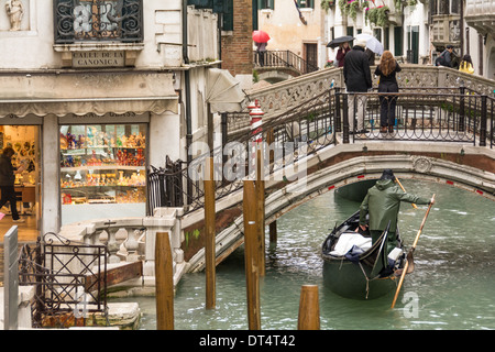 Venise, Italie. Gondola sur canal étroit, de verre de Murano boutique, personnes avec umbralla sur des petits ponts sur un jour de pluie. Banque D'Images