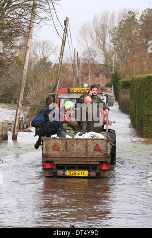 Burrowbridge, Somerset, UK - 9e mai 2014. L'équipe de support et les villageois partagent un trajet en remorque transportant des sacs de pièces inondées de Burrowbridge village. Banque D'Images
