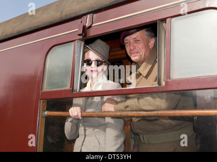 Deux personnes à la recherche d'une fenêtre de train en costume des années 1940 Banque D'Images