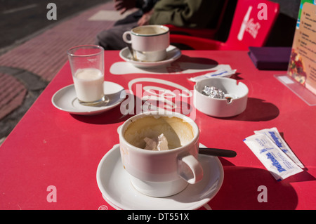 Tasses à café sale sur une table à l'extérieur de coca cola un café. Banque D'Images