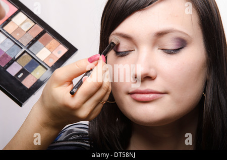 Offres d'artiste de maquillage maquillage sur le visage du modèle. Elle peint les ombres de la paupière supérieure modèle. Banque D'Images