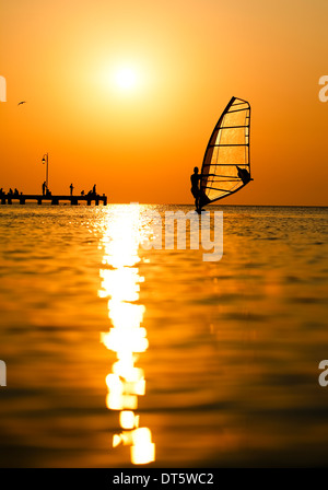 Silhouette de surfer au coucher du soleil en passant par Banque D'Images