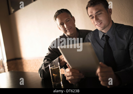 Deux collègues looking at digital tablet in wine bar Banque D'Images