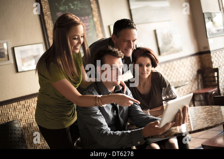 Friends looking at digital tablet in wine bar Banque D'Images