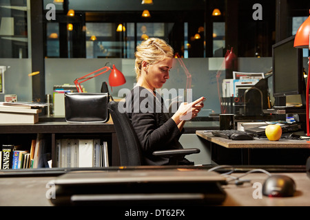 Female office worker at desk using cell phone Banque D'Images