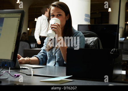 Young woman drinking coffee in office Banque D'Images