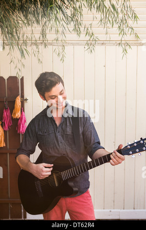 Young man playing acoustic guitar in garden Banque D'Images