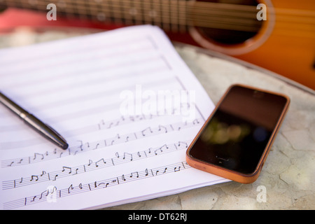 Image recadrée de guitare, smartphone et partitions Banque D'Images