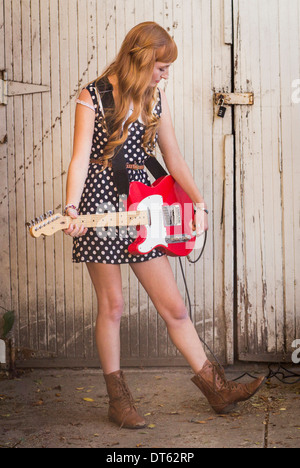 Young woman playing electric guitar in yard Banque D'Images