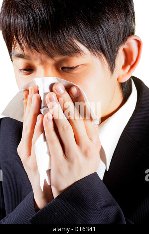 Young Asian Man Blowing Nose dans un mouchoir Banque D'Images