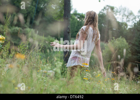 Teenage girl walking sur les fleurs sauvages Banque D'Images