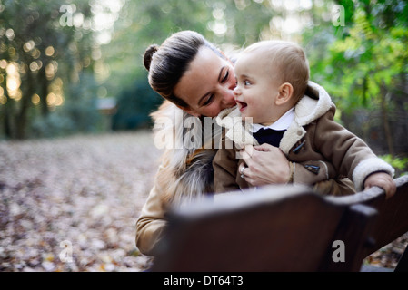 Holding mère enfant mâle sur le banc de parc Banque D'Images
