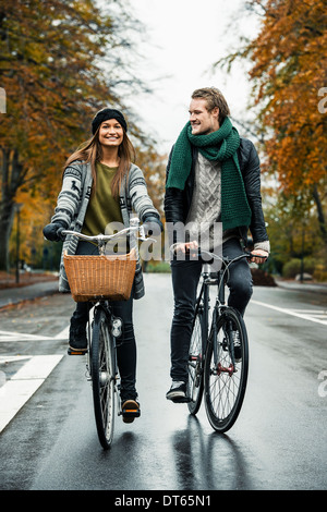 Jeune couple cycling on street Banque D'Images